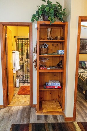 A wooden shelving unit with a plant on top, a pair of boots, and various items including a box labeled "SEQUENCE". - The Love Shack (Sautee Nacoochee)