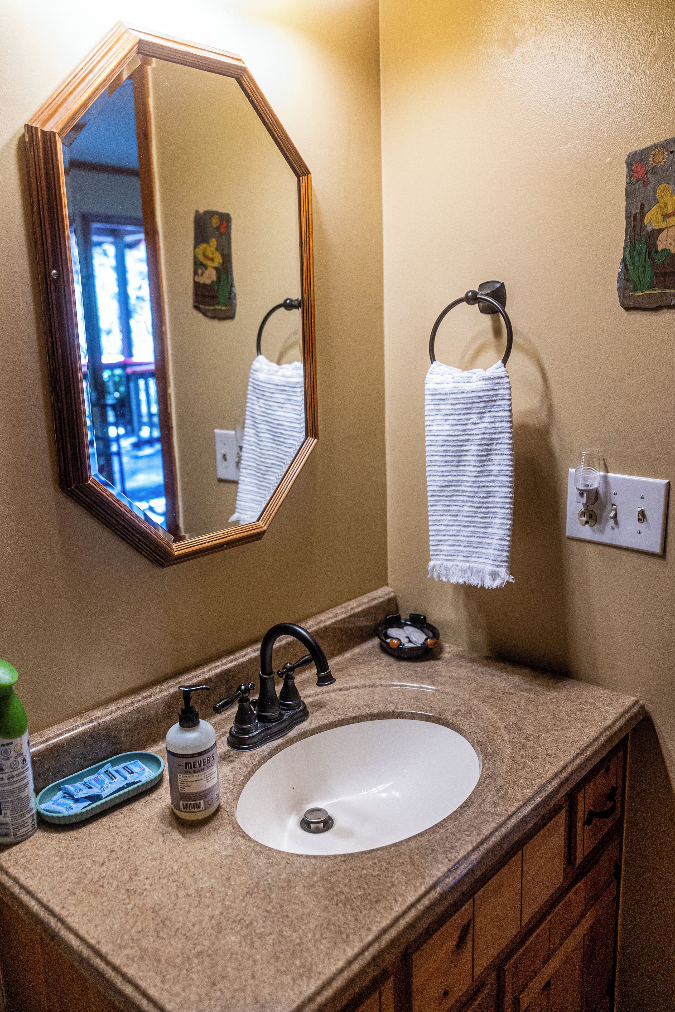 A bathroom with a sink, mirror, towel rack, and toiletries.