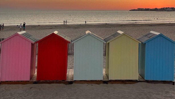 Una spiaggia con vivaci chioschi e un tramonto sull'oceano.