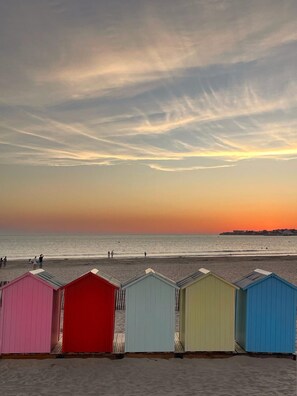 A beach with colorful beach huts and a sunset over the ocean. - Two-bedroom apartment with a terrace near Grande Conche Beach in the Quartier du Parc neighborhood (Royan)