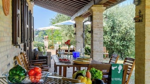 Eine Terrasse im Freien mit Esstisch, umgeben von Holzstühlen und einer Ziegelwand.