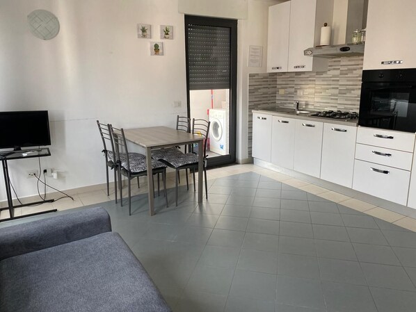 A modern kitchen with white cabinets, a stove, and a washing machine. - Bright and spacious to visit Rome (Vitinia)