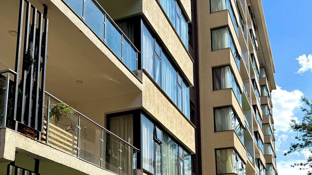 Un immeuble résidentiel à plusieurs étages, doté de balcons, de grandes fenêtres et d’un trottoir dallé.