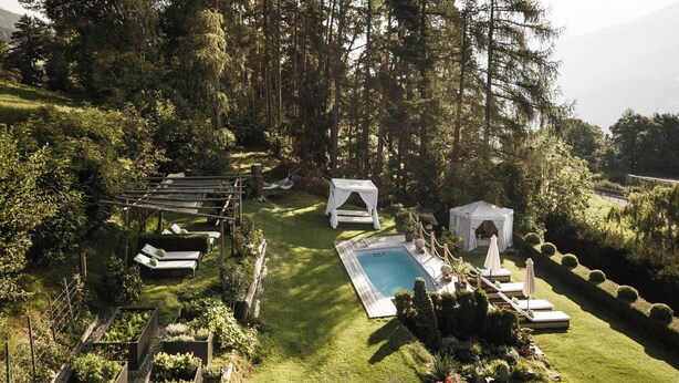 Un jardin bien entretenu, doté d’une piscine, de chaises longues et d’un belvédère.