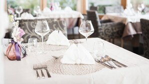 Un espace repas avec des tables dressées pour le service, agrémenté de nappes blanches, de couverts en argent et de verres à vin.