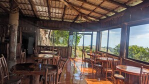 A rustic wooden interior with large windows offering a view of the outdoors.