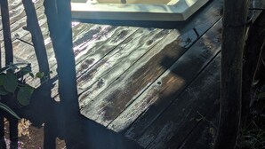A hot tub on a wooden deck with a wooden railing surrounding it.