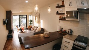 Een moderne keuken met houten aanrecht, een inbouwoven en een zithoek met een bank en eettafel.