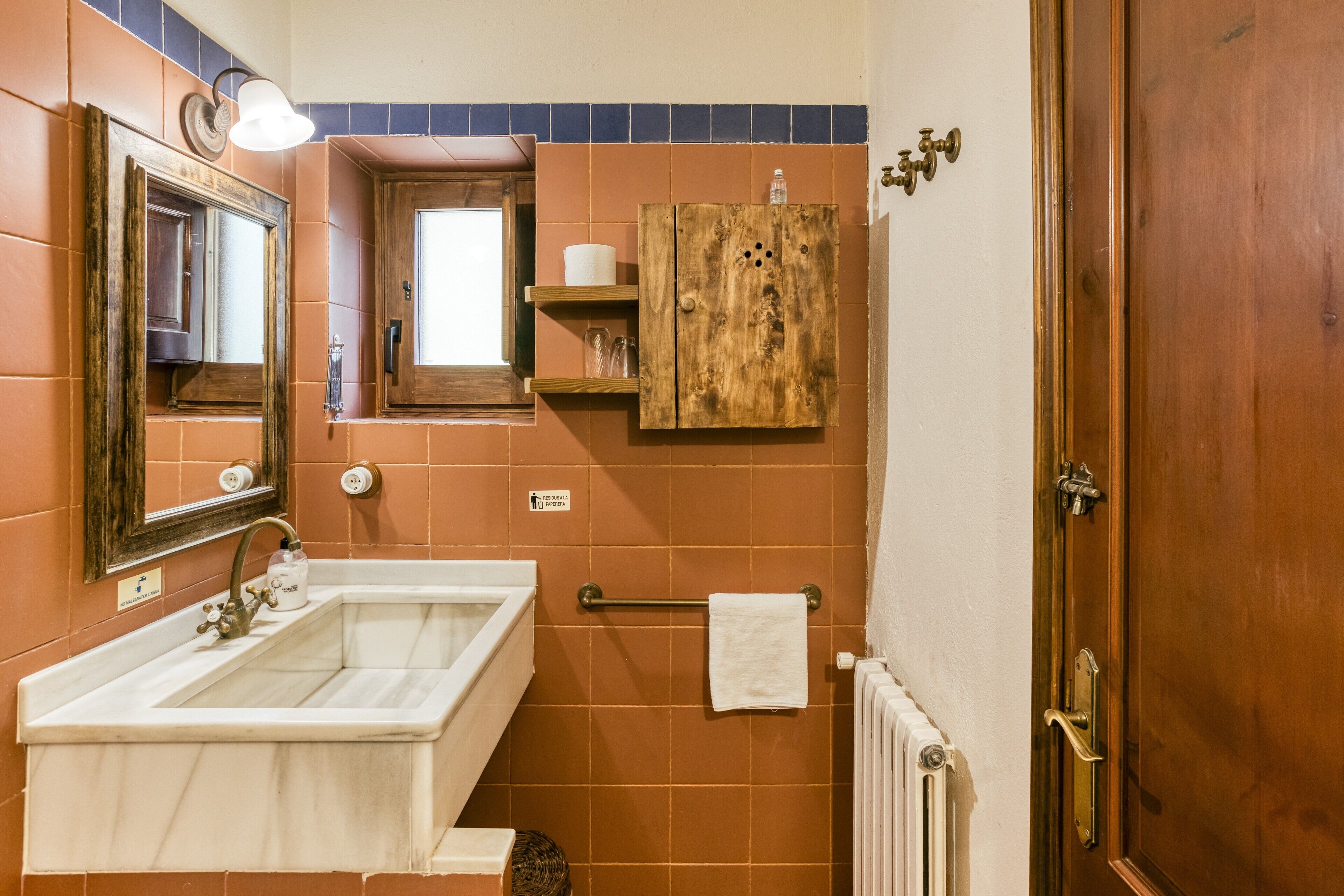 Un baño con lavamanos, espejo, toallero y mueble de madera.