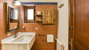Un baño con lavamanos, espejo, toallero y mueble de madera.