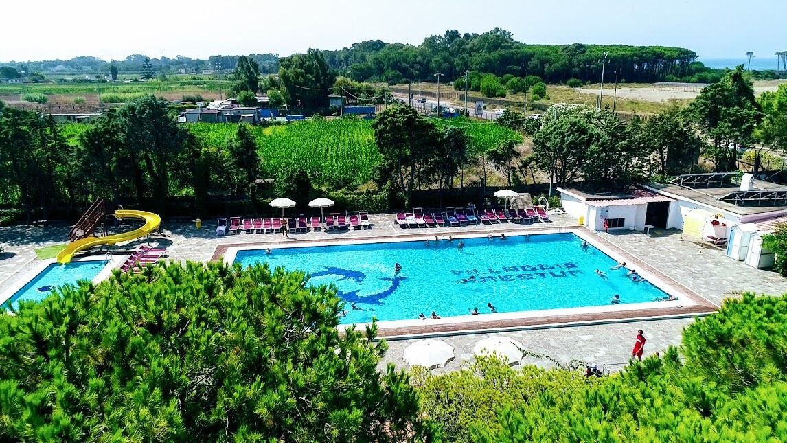 A swimming pool with a yellow slide, surrounded by lounge chairs and umbrellas.