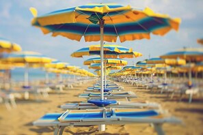 Ein Strand mit Liegestühlen und gestreiften Sonnenschirmen.