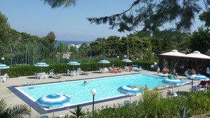 A swimming pool with lounge chairs and umbrellas, surrounded by trees and a view of the sea. - Camping Village San Menaio Mobilehome Happy Easy for 6 people (San Menaio)