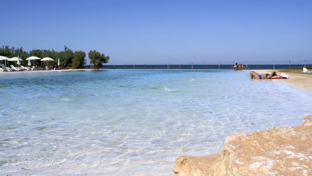 Une plage avec une eau cristalline, des chaises longues et des parasols.