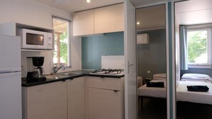 Une cuisine compacte équipée d’un four à micro-ondes, d’une cuisinière et d’un évier. Un petit coin repas avec une table et des chaises est également prévu. La pièce comprend également un lit avec une fenêtre.