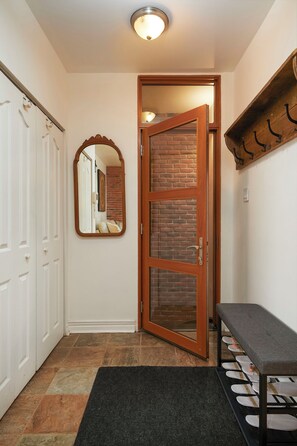Enter a cozy space with a brick wall, wooden door, and a bench for resting.