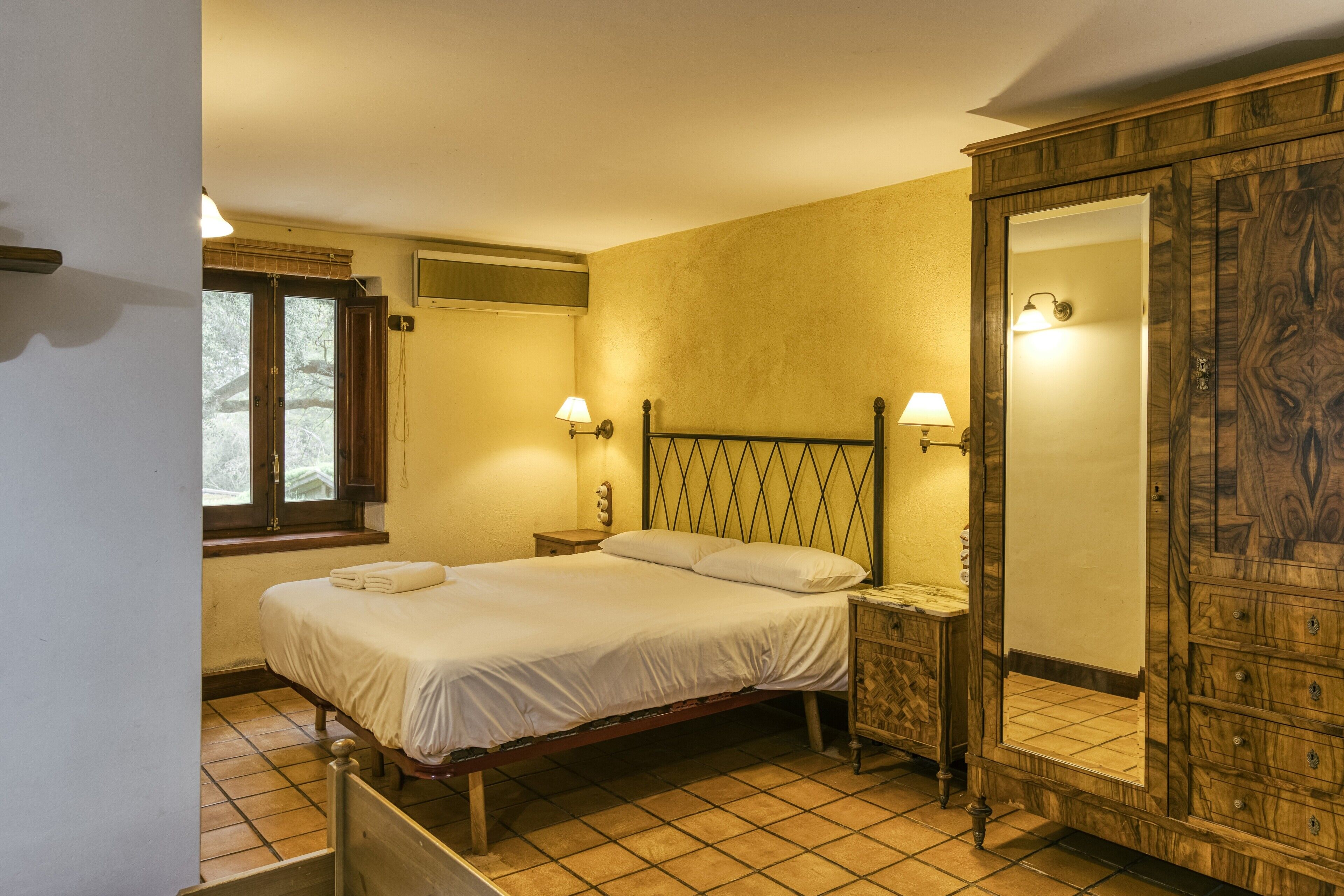 Een slaapkamer met een bed, bedlampen, een kledingkast en een raam met uitzicht.
