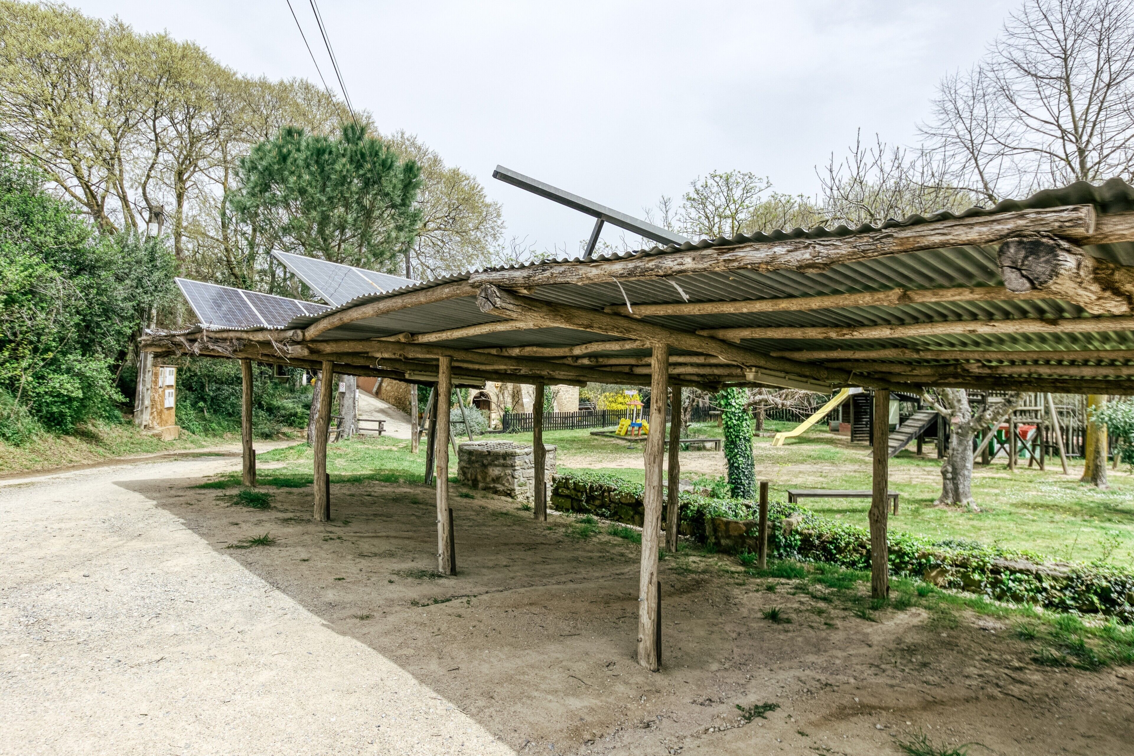 A rustic outdoor shelter with a corrugated metal roof supported by wooden beams.