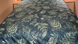 Ein Schlafzimmer mit einem Bett, einem Holzkopfbrett, zwei Nachttischen und einem Karomuster-Vorhang.