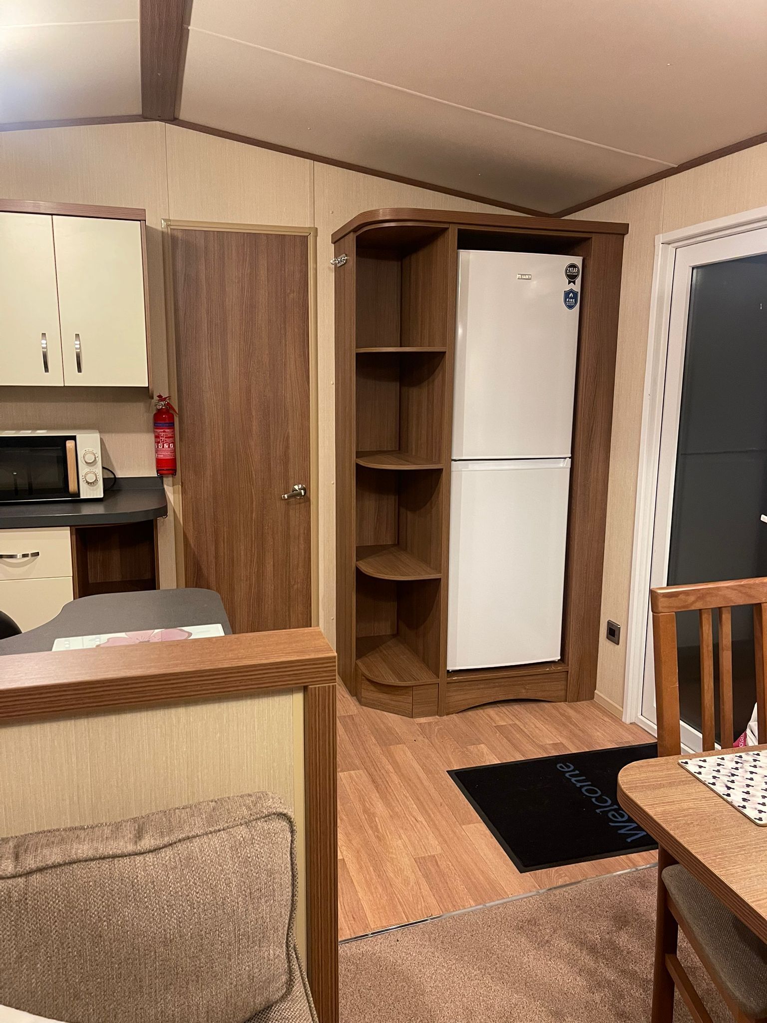 A compact kitchen with a microwave, a white refrigerator, and wooden cabinets.