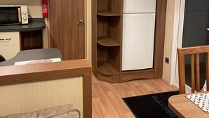 Eine kompakte Küche mit einer Mikrowelle, einem weißen Kühlschrank und Holzschränken.