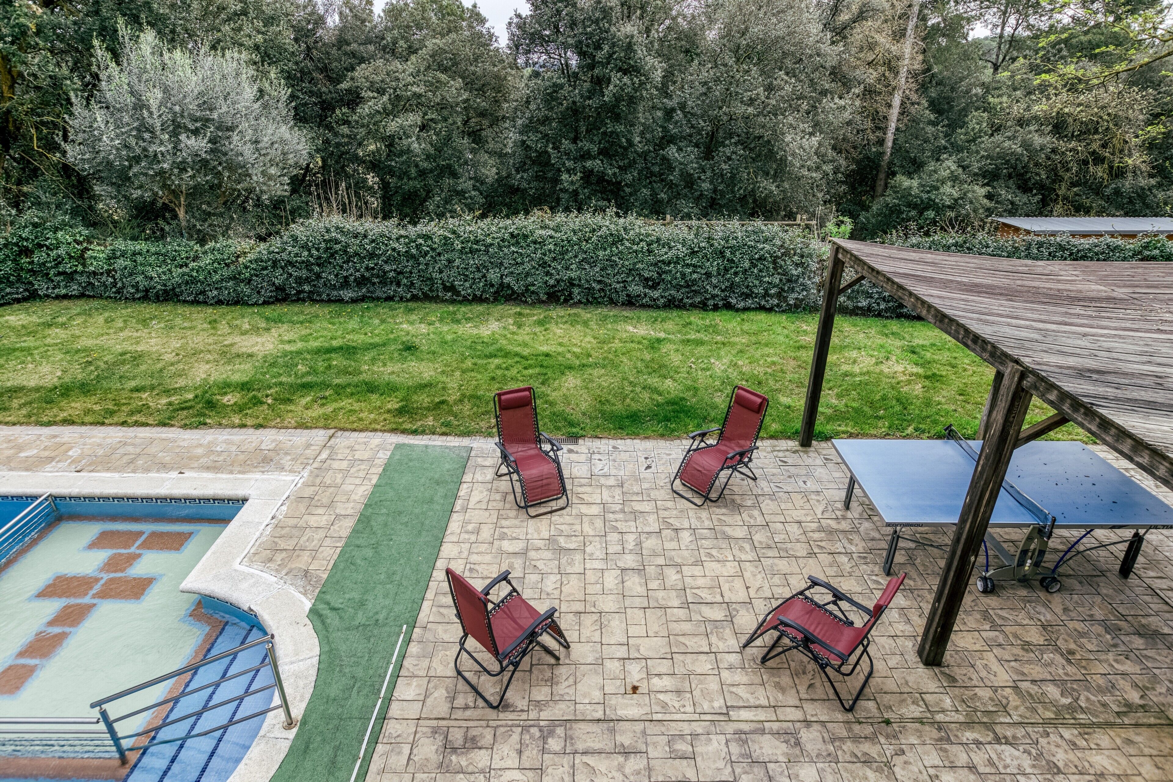 Une terrasse extérieure avec une piscine, des chaises longues et un espace abrité.