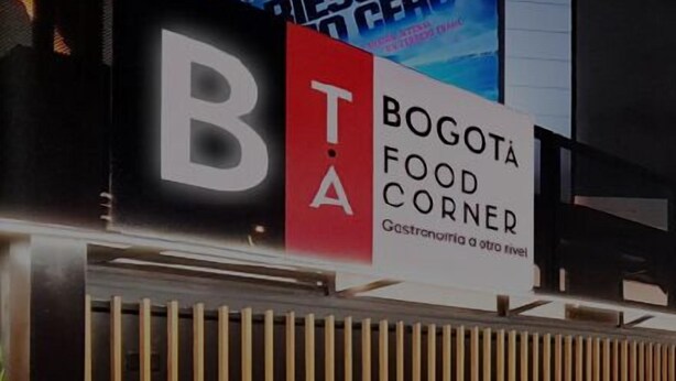 Un restaurant appelé « Bogota Food Corner », avec une façade en bois à lambris verticaux et des plantes en pot devant l’entrée.