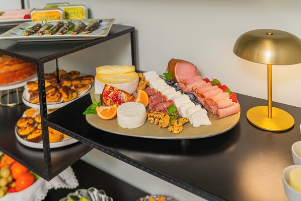 Una mesa de buffet con diversos alimentos, como queso, carnes y pasteles.