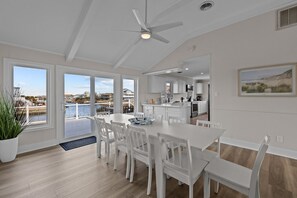 A spacious kitchen with white cabinetry, a dining area with white chairs, and a view of a waterfront. - NEW! Boat Ramp, Pool, Hot Tub (Virginia Beach)