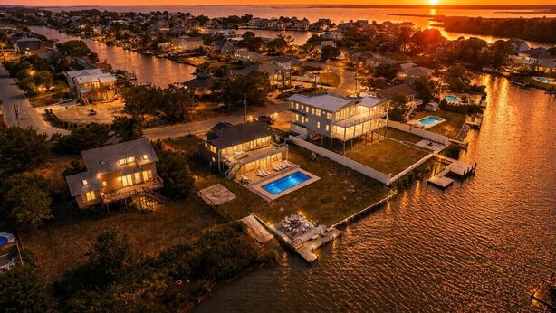 En fastighet vid vattnet med flera hus, en swimmingpool och en brygga.