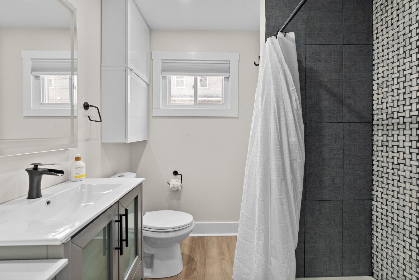 A modern bathroom with a white sink, toilet, and shower curtain.