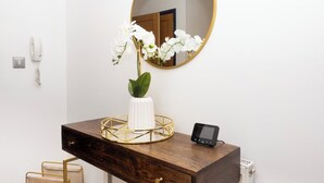 A bathroom with a wooden vanity, a round mirror, a white vase with flowers, a black phone, and a gold-framed tray. - Ramsgate boutique  (Ramsgate)
