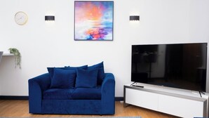 A modern living room with a blue sofa, a flat-screen TV, and a colorful abstract painting on the wall. - Ramsgate boutique  (Ramsgate)
