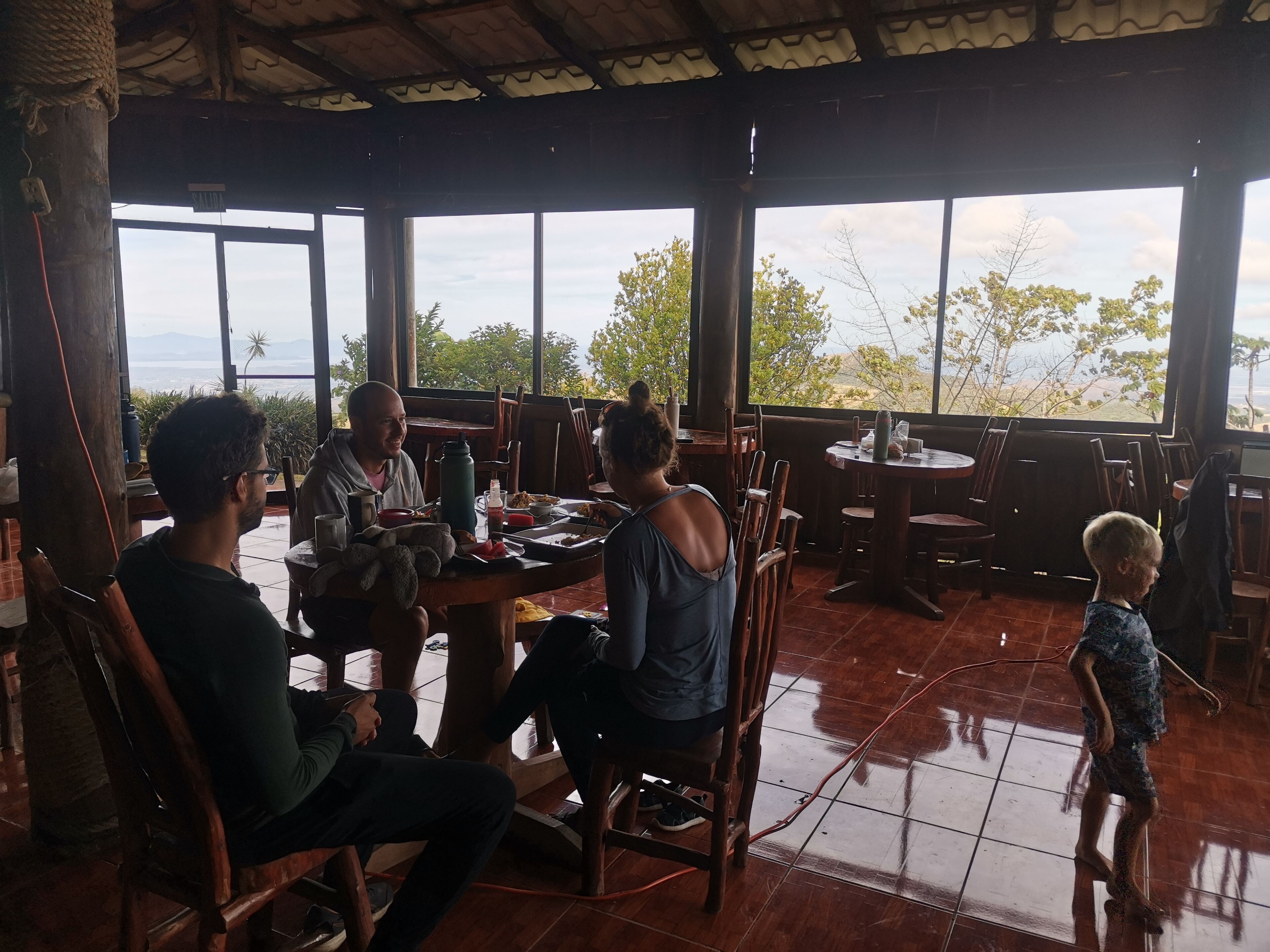 A family dining at a restaurant with large windows offering a view of the outdoors.