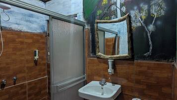 Un baño con ducha, lavamanos, inodoro y espejo decorado con una pintura.