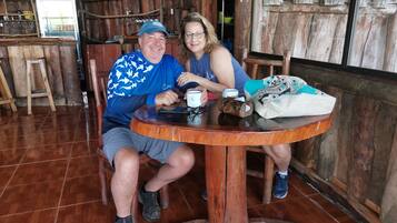 A rustic wooden interior with a round wooden table, chairs, and a refrigerator.