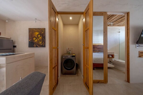 A compact room with a washing machine, a bed, and a small bathroom.
