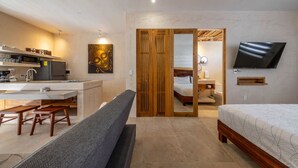 Ein modernes Hotelzimmer mit Küchenzeile, einem großen Bett, einem Fernseher und einem Holzschrank.
