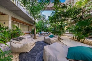 An outdoor lounge area with covered seating and lush greenery.