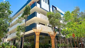 Un immeuble moderne à plusieurs étages, doté d’un toit plat, de grandes fenêtres et d’un balcon aux étages supérieurs.