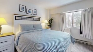 A bedroom with a bed, bedside tables, a window with curtains, and wall-mounted pictures. - Killington Sapphire (Killington)