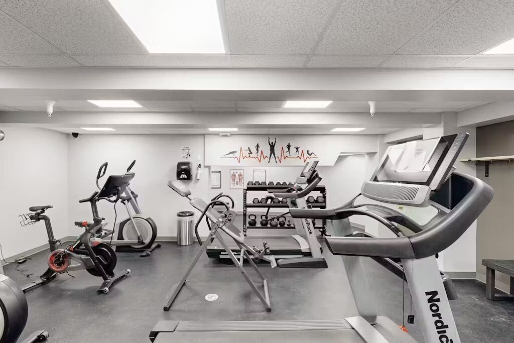 Une salle de sport équipée de vélos d’appartement, de tapis de course et d’appareils de musculation.