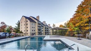 A swimming pool with a modern design, surrounded by a fenced area and a multi-story building with balconies. - Killington Sapphire (Killington)
