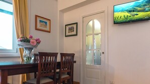 Et spiseområde med et træbord og stole, en vase med blomster og et indrammet billede på væggen.