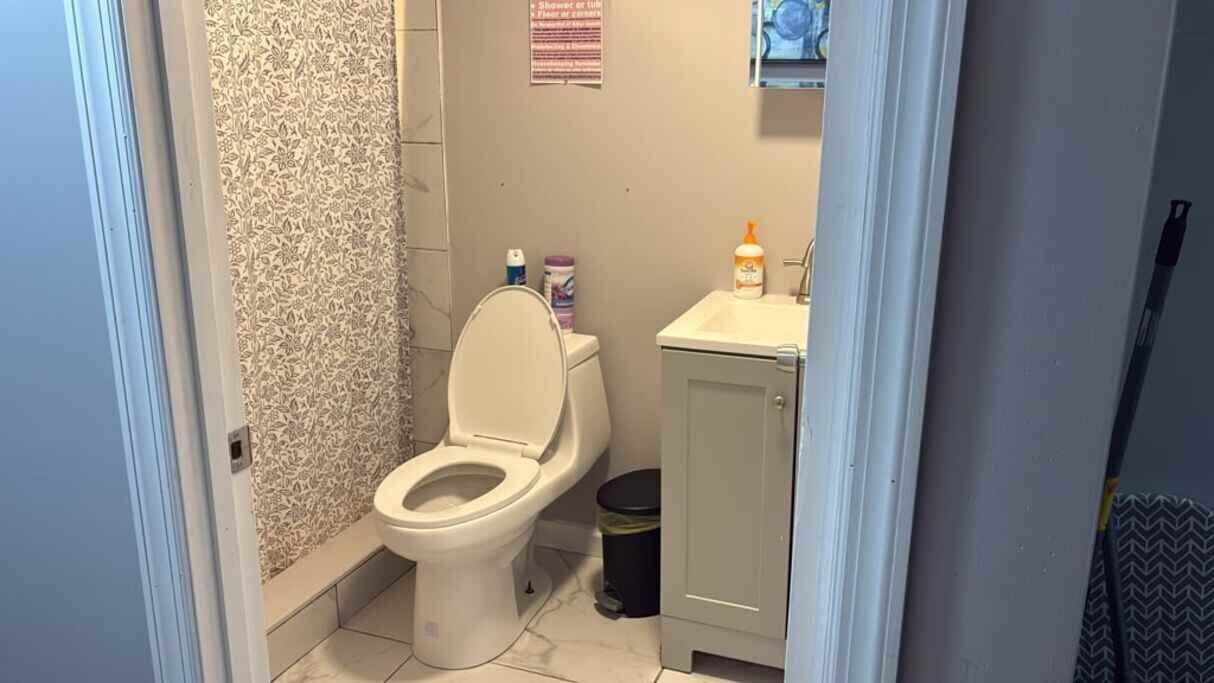 Un baño con inodoro, lavamanos y cubo de basura.