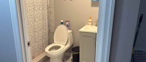 Et badeværelse med toilet, vask og skraldespand.