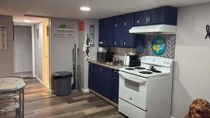 A compact kitchen with dark blue cabinets, a white stove, and a microwave. - Classic Room E | Near MetLife, EWR & NYC Access (Newark)