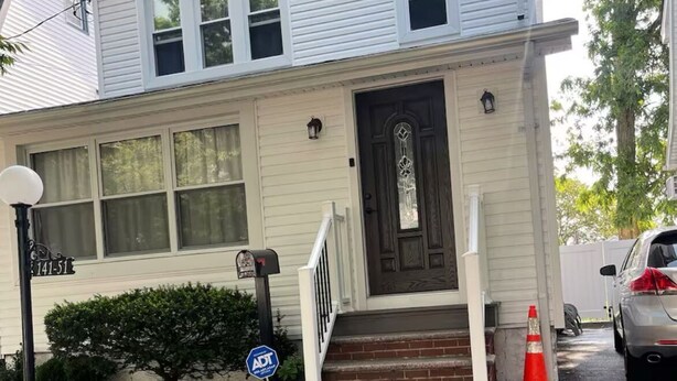 A two-story house with a front porch, a mailbox, and a street sign. - Charming 1-bedroom in a private house in Queens with AC, WiFi. Enjoy your stay (Queens)