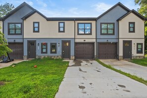 A modern two-story house with a garage, a well-maintained lawn, and a concrete driveway.