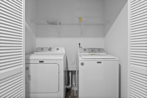 A laundry room with two Maytag washing machines and a metal pipe.